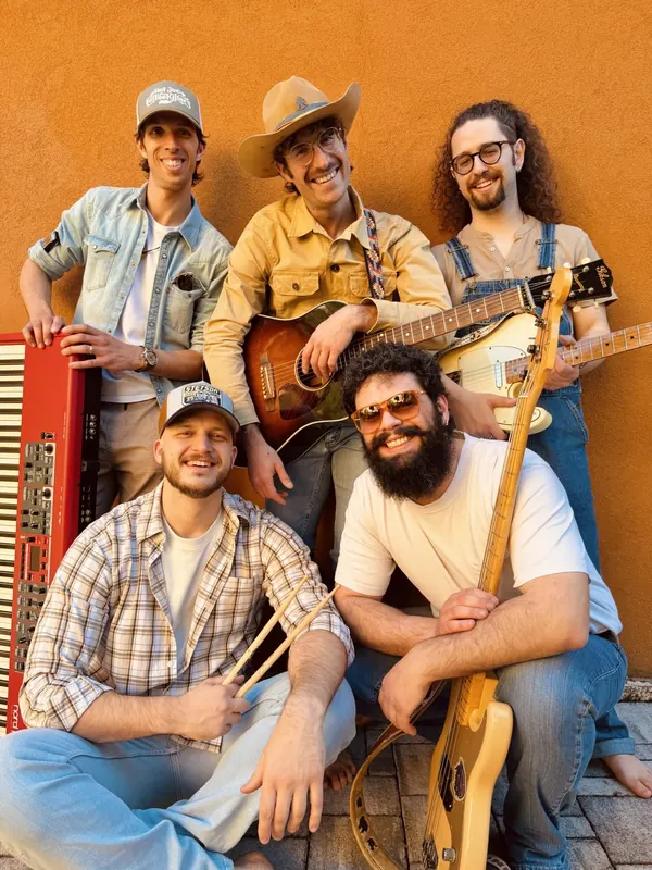 Portrait of the whole country band Hot Joe & The Coffeekillers with their instruments, against a terracotta wall