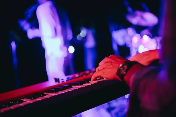 Close-up of Larry&rsquo;s hands on the keys during a show, red and purple lights