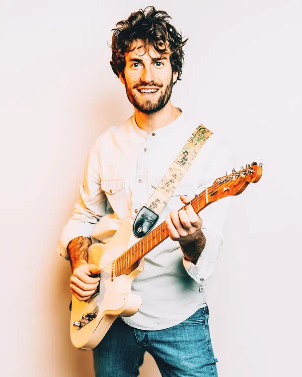 Studio portrait of Mike smiling with his Telecaster and decorated strap