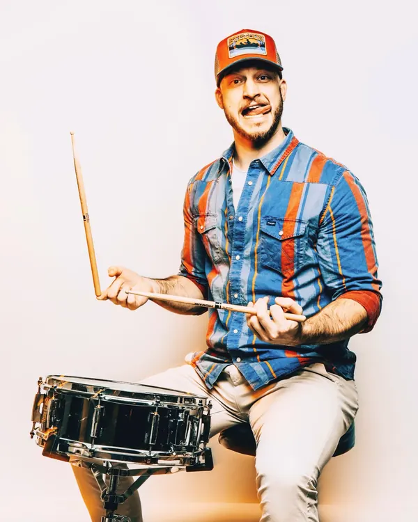 Studio portrait of Miglio sitting with a snare drum and sticks