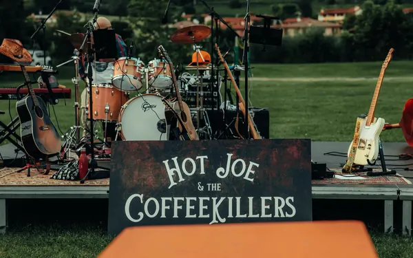 L'insegna in legno dipinta a mano Hot Joe & The Coffeekillers davanti al palco allestito su un prato