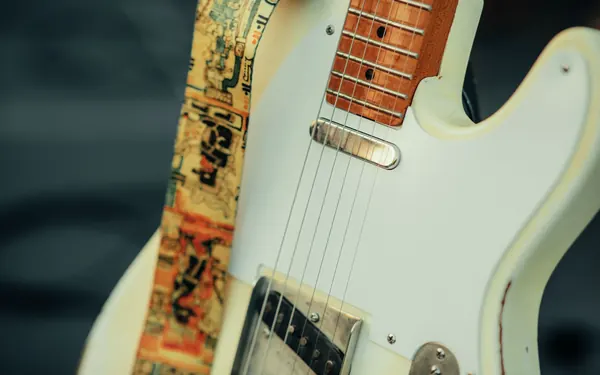 Close-up of a well-worn white Telecaster with a decorated strap