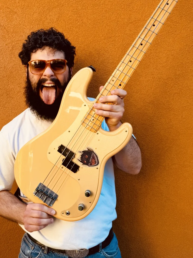 Riccardo &ldquo;Richi&rdquo; Loda che alza il basso con la lingua di fuori, davanti a un muro arancio